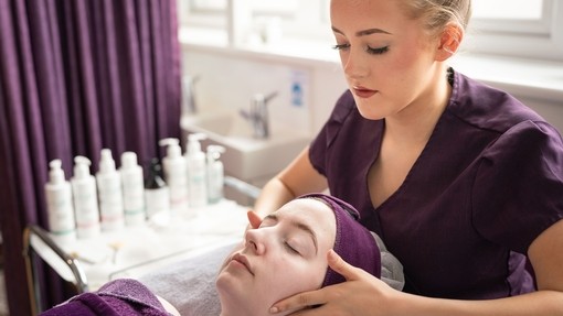 Close up of student in purple uniform giving someone a facial.