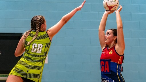 Two female students playing netball. One marking the other as she aims to shoot the ball.