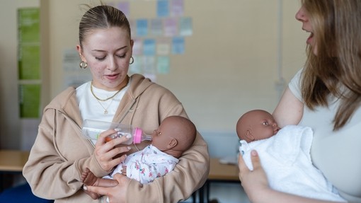 Student cradling dummy baby with baby bottle