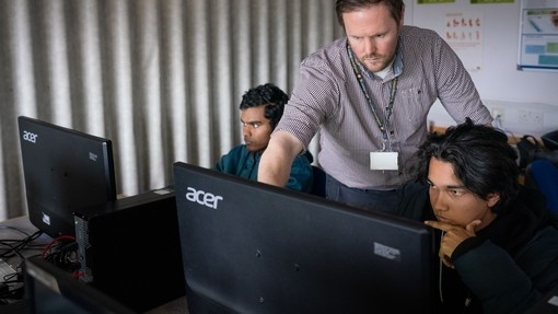 Tutor helping student sat at computer