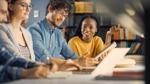 a groupf diverse young adults studying in a library setting
