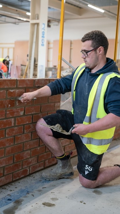 Student laying bricks in workshop