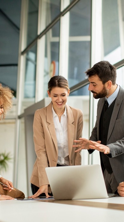 A group of people in an office discussing a laptop