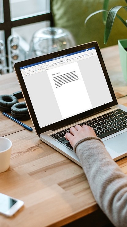 A woman with brown hair using Microsoft Word on a laptop