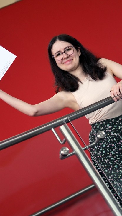 Ella standing on the stairs waving her results