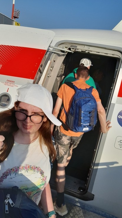 Students boarding a plane with one looking at the camera with a thumbs up