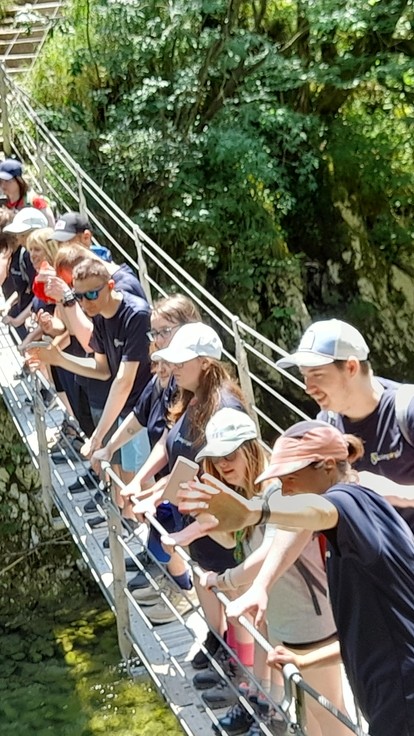Students looking down over a rope bridge with greenery behind