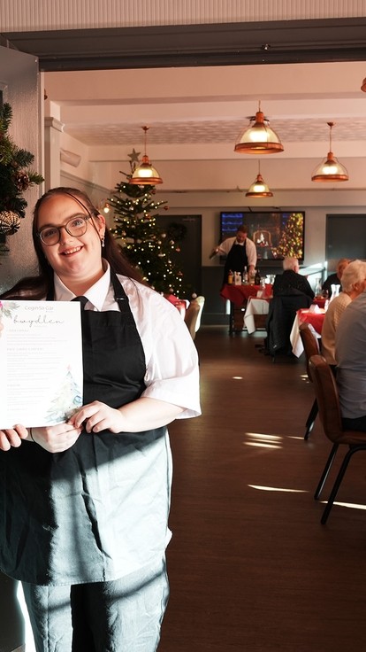 Two students standing at the entrance of the restaurant holding a menu