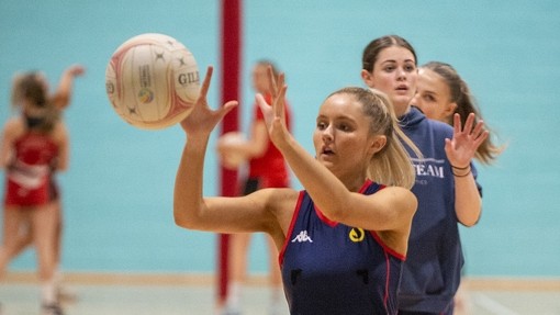 Student playing netball in the sports hall.