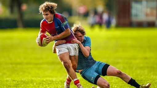 Two students playing rugby, one is tackling the other.