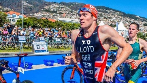Student athlete in a Team GB sports kit and red swimming cap, racing in a triathlon.