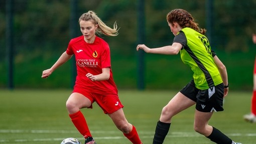 Two female student athletes playing football.