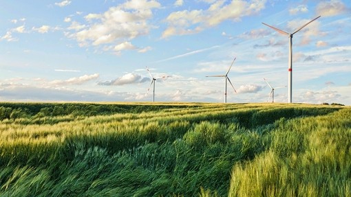 Wind turbines visible in a green field. It's a nice day with clouds in the blue sky