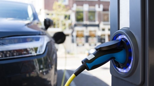 Close-up of the electric vehicle charging point, the car charging is visible to the left