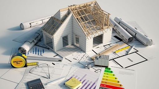 Small scale model of a house, with a tape measure and efficiency scale