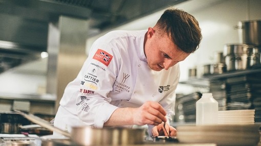 Sam in the kitchen putting final pieces to his dish