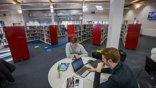 high up shot of a man working at a desk in the library