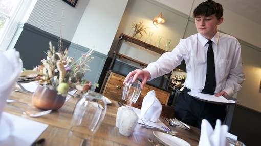 Student laying a table in a training restaurant