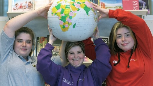 three students holding a blow up globe
