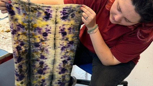 Student holding a colourful piece of fabric in her hands, showcasing its texture and design