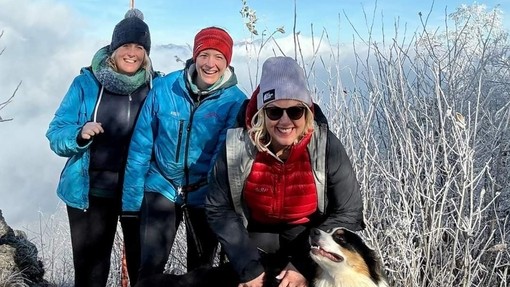 Three people dressed for the cold in a cold environment with a dog