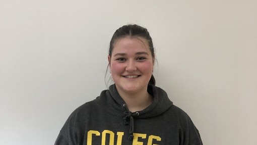 student in Coleg Cenedlaethol hoodie (grey and yellow) looking at the camera