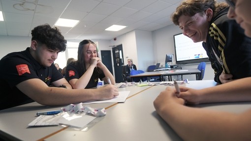 Three learners sat around a table participating in a workshop and writing on a big a2 paper
