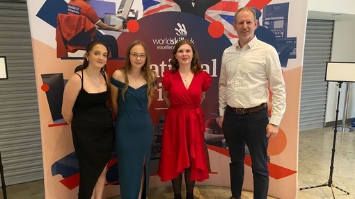 Huw Morgan, catering lecturer in front of a national winners stand with his students