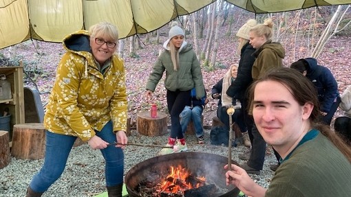 Philippa around a fire with some students looking jovial.