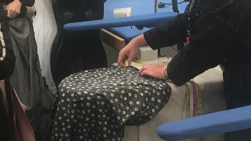 A tutor helping a student with a garment