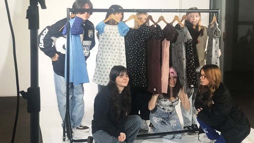 Students standing by a clothes rail on an area used to take photos