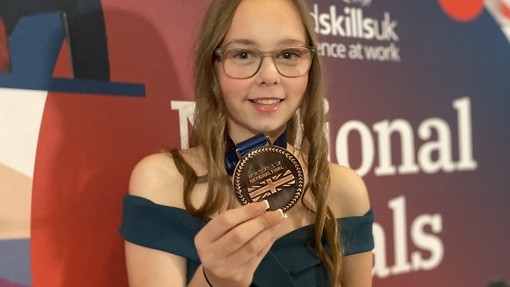 Shannon holding her bronze medal with a WorldSkills UK backdrop