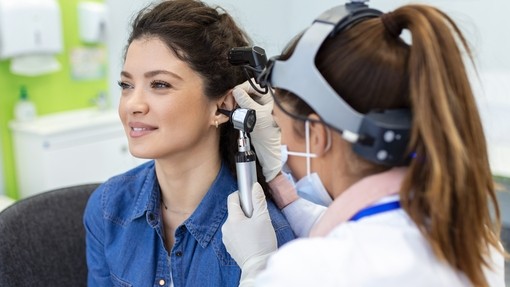 Audiologist wearing headgear giving an ear exam