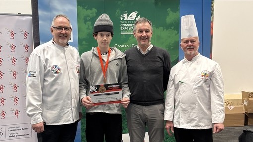 Finn standing with chefs wearing a competition medal