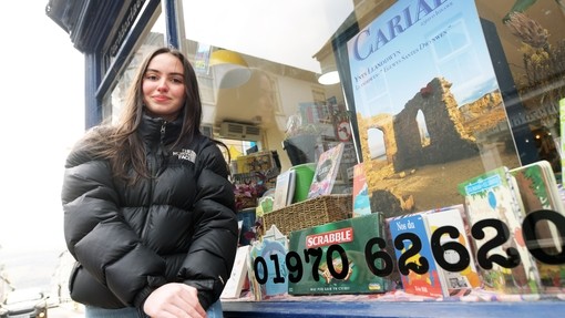 Student outside a shop window in Aberystwyth town