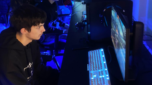 Students in the esports room it's dark with lots of bright colours coming from the screens and keyboards