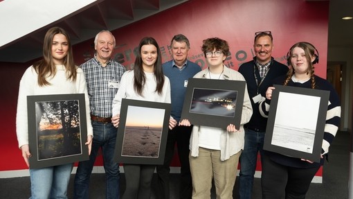 Winning students holding up their artwork with lecturer Simon and two people from the photo society