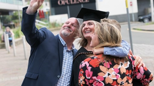 A family taking a celebratory selfie at graduation.