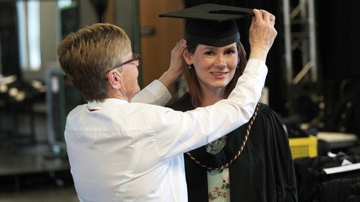 a young lady getting her cap fitted for graduation
