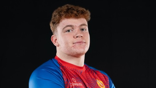 Osian in his kit looking at the camera with folded arms