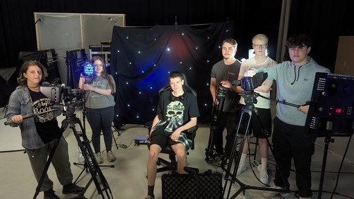 A group of students next to various apparatus in the college media studio