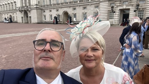 A selfie of Rob and his wife all dressed up with a royal residence in the background