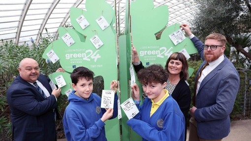 People standing around a cardboard tree with their green24 pledges