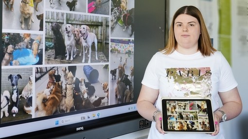 Claire next to a screen with dogs on and holding