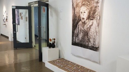 Jenny's whole exhibition space which consists of a portrait in charcoal and clay shoes and vase and sunflowers