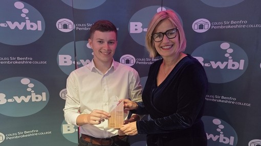 Guto at the awards with branded background with vice principal Vanessa