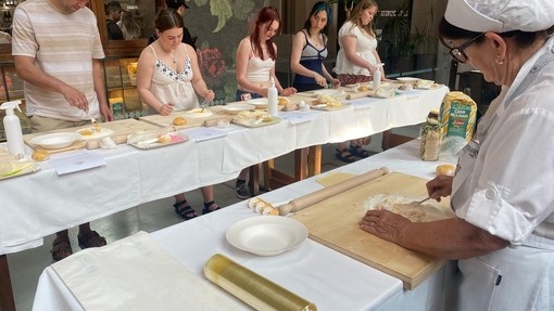 An Italian lady demonstrating pasta making with students ready at their stations