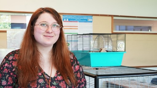Tegan standing next to a couple of comparison cages