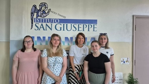 Five students standing under an Italian sign indoors
