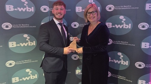 Euan with Vanessa Cashmore, Vice Principal receiving his work based learning award against a logo branded backdrop